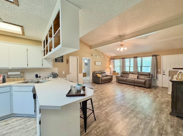 702 Pleasant Grove Rd, Elgin, TX 78621 - kitchen featuring a textured ceiling, a ceiling fan, a breakfast bar area, light countertops, and light wood-type flooring