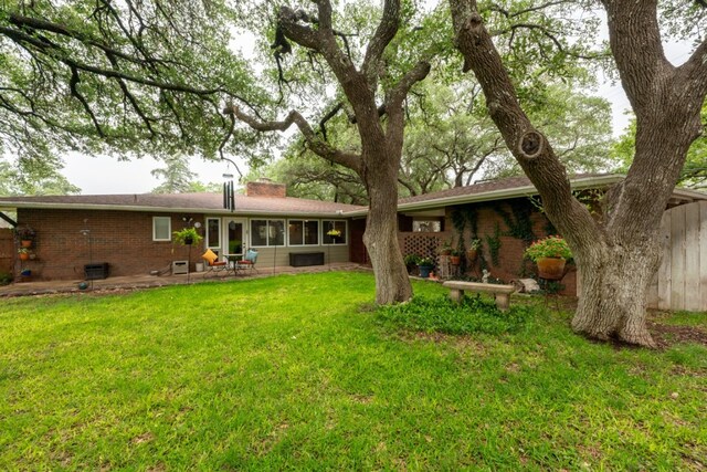 507 Flamingo Cir, Marble Falls, TX 78654 - rear view of property featuring brick siding, a chimney, a yard, and a patio