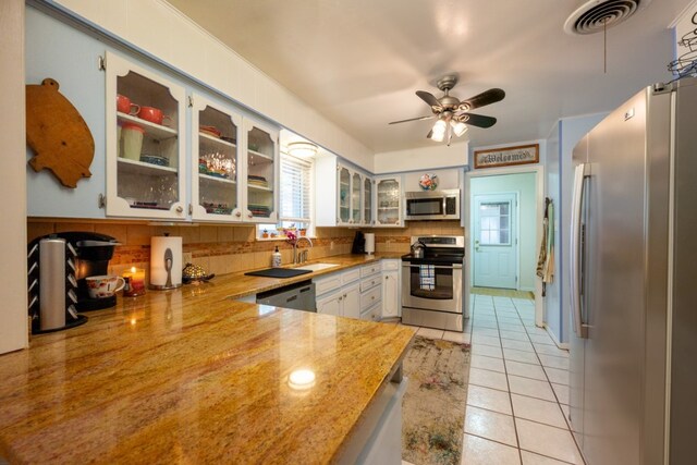 507 Flamingo Cir, Marble Falls, TX 78654 - kitchen with stainless steel appliances, backsplash, light tile patterned flooring, a ceiling fan, and glass insert cabinets