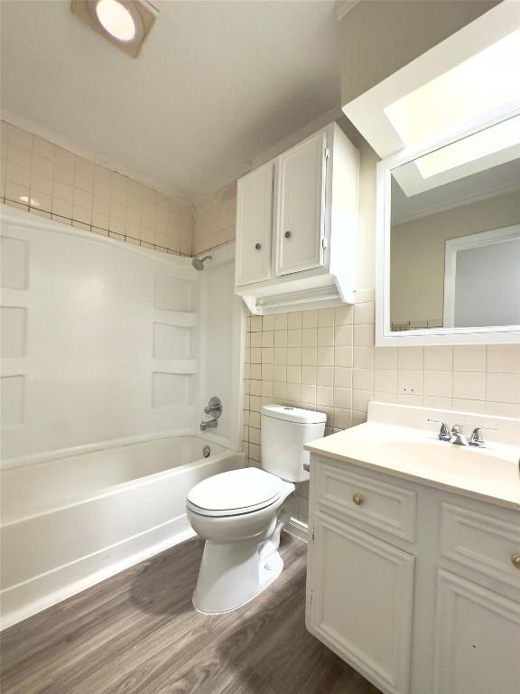 4503 E Stassney Ln, Austin, TX 78744 - bathroom with wood finished floors, vanity, bathtub / shower combination, tasteful backsplash, and tile walls