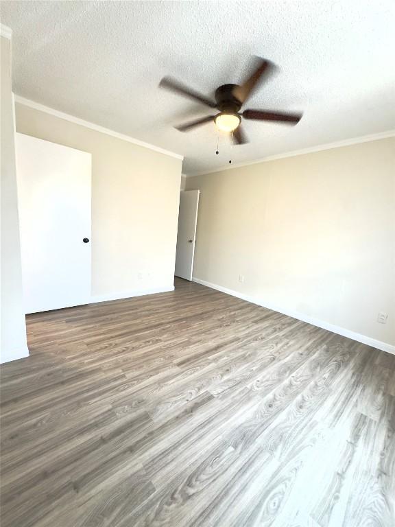 4503 E Stassney Ln, Austin, TX 78744 - empty room featuring wood finished floors, ornamental molding, ceiling fan, and a textured ceiling