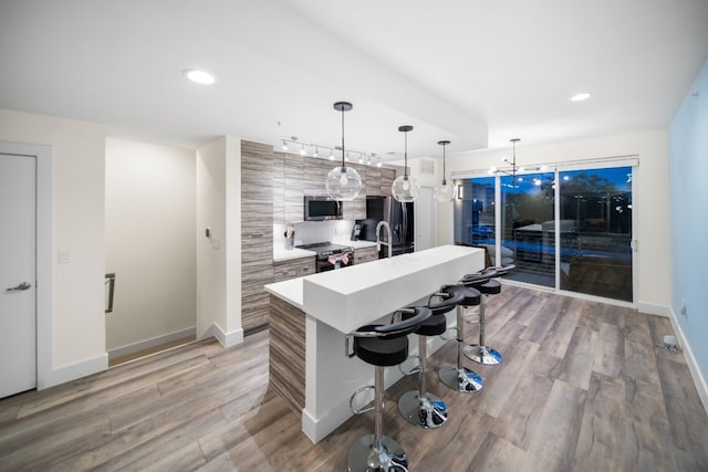 604 N Bluff Dr Unit 247, Austin, TX 78745 - kitchen featuring stainless steel appliances, an island with sink, light wood-style flooring, a breakfast bar area, and light countertops