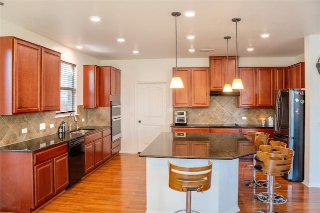 1529 Gautami Dr, Austin, TX 78753 - kitchen featuring appliances with stainless steel finishes, a kitchen island, light wood-style floors, a kitchen breakfast bar, and recessed lighting