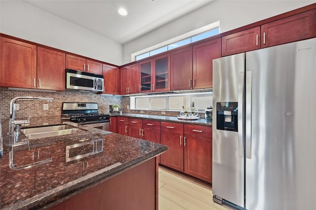 1115 Kinney Ave Unit 6, Austin, TX 78704 - kitchen featuring stainless steel appliances, backsplash, dark stone counters, reddish brown cabinets, and glass insert cabinets