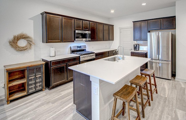 261 Deserti Rd, Leander, TX 78641 - kitchen with appliances with stainless steel finishes, light wood finished floors, a breakfast bar, dark brown cabinets, and recessed lighting