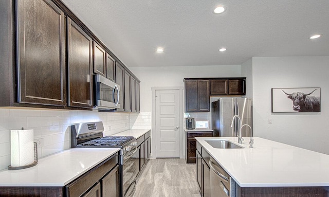 261 Deserti Rd, Leander, TX 78641 - kitchen with stainless steel appliances, an island with sink, dark brown cabinetry, tasteful backsplash, and light countertops