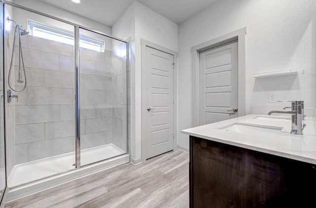 261 Deserti Rd, Leander, TX 78641 - bathroom featuring a stall shower, double vanity, and wood finished floors