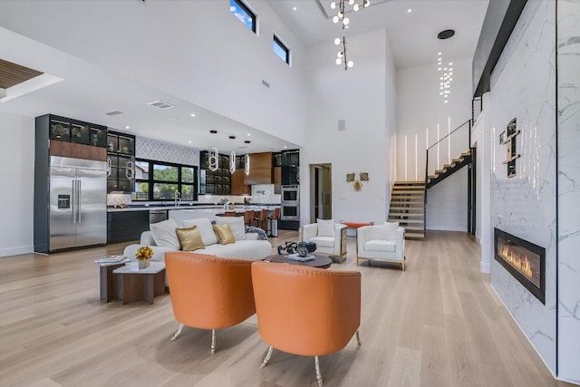 1806 Lauren Dr, Spicewood, TX 78669 - living area with light wood finished floors, stairs, a fireplace, and a towering ceiling