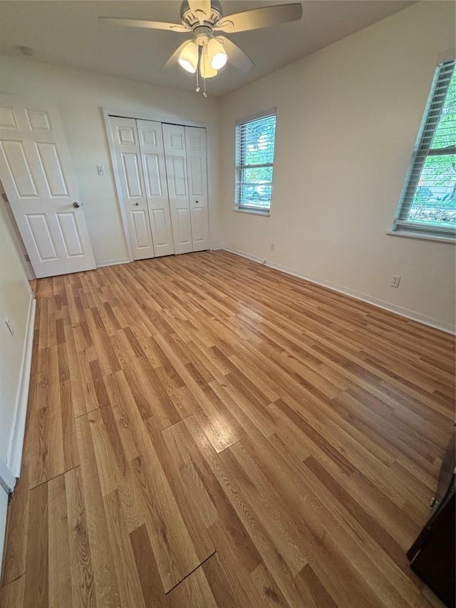 3205 Whites Dr, Austin, TX 78735 - unfurnished bedroom with light wood finished floors, multiple windows, ceiling fan, and a closet