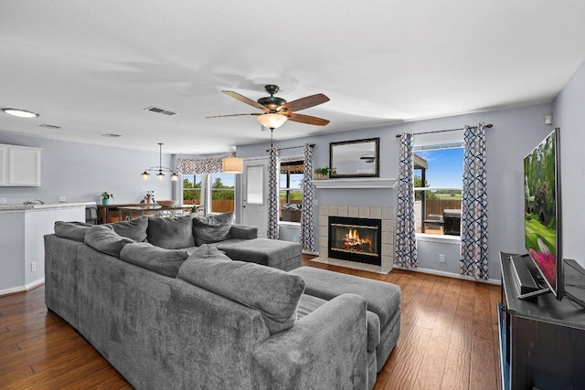 906 Pecos Cv, Leander, TX 78641 - living area with a tile fireplace, dark wood finished floors, and ceiling fan