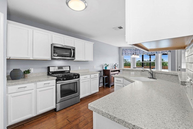 906 Pecos Cv, Leander, TX 78641 - kitchen with appliances with stainless steel finishes, white cabinetry, dark wood-style flooring, and light countertops