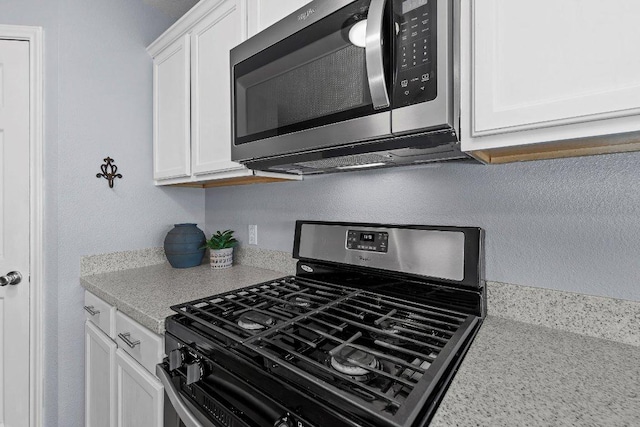 906 Pecos Cv, Leander, TX 78641 - kitchen with stainless steel appliances, white cabinets, and a textured wall
