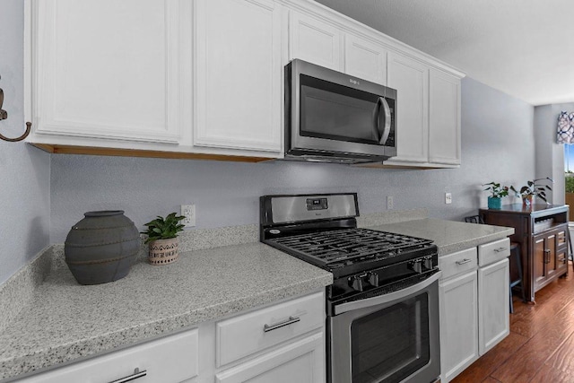 906 Pecos Cv, Leander, TX 78641 - kitchen featuring appliances with stainless steel finishes, white cabinetry, light countertops, and dark wood-style flooring