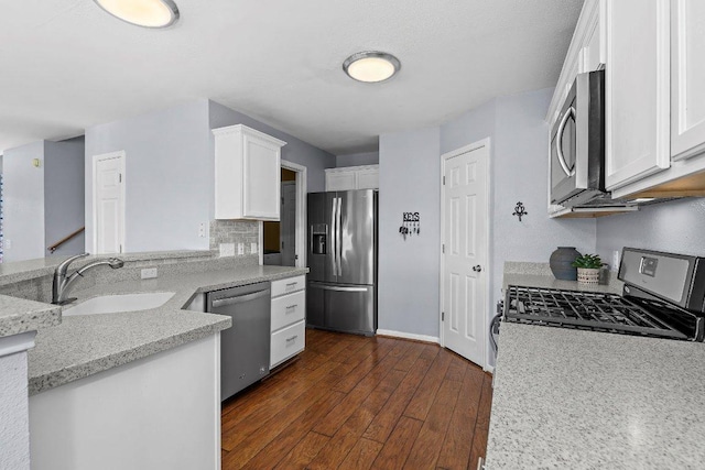 906 Pecos Cv, Leander, TX 78641 - kitchen with stainless steel appliances, white cabinets, dark wood-style floors, light stone countertops, and a peninsula