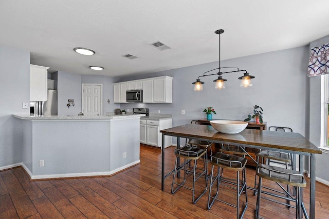 906 Pecos Cv, Leander, TX 78641 - kitchen featuring appliances with stainless steel finishes, dark wood-style floors, white cabinetry, and a peninsula