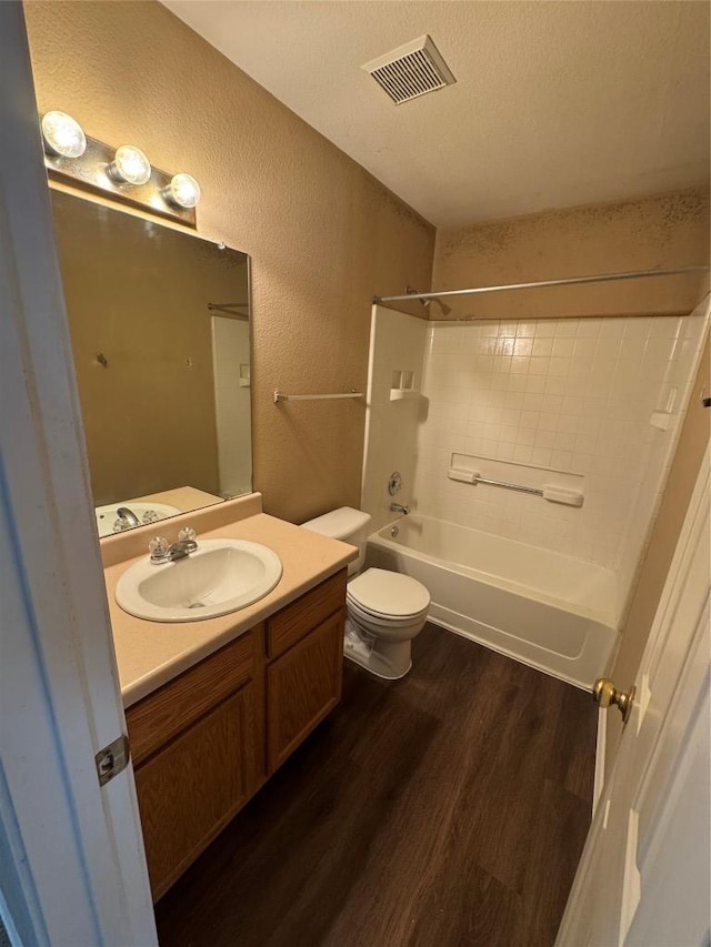 209 Lake Washington Dr, Kyle, TX 78640 - bathroom featuring wood finished floors, a textured wall, vanity, shower / bathtub combination, and a textured ceiling