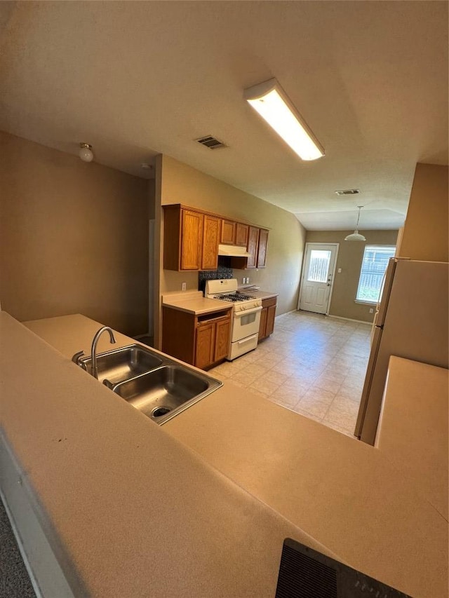 209 Lake Washington Dr, Kyle, TX 78640 - kitchen with gas range gas stove, brown cabinets, under cabinet range hood, light flooring, and light countertops