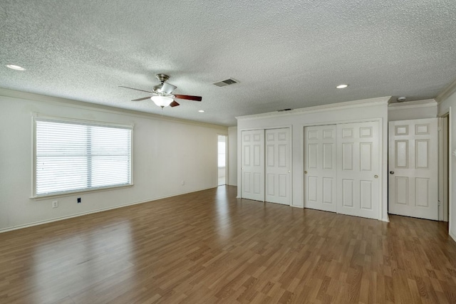 2801 Adelen Ln, Round Rock, TX 78664 - unfurnished bedroom with crown molding, multiple closets, wood finished floors, a textured ceiling, and recessed lighting