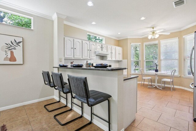136 Trail Of The Flowers, Georgetown, TX 78633 - kitchen featuring dark countertops, under cabinet range hood, tasteful backsplash, white cabinets, and recessed lighting
