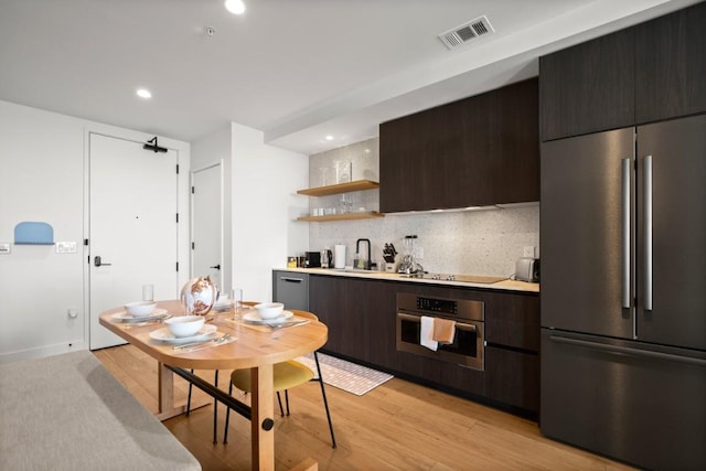 48 E Ave Unit 2707, Austin, TX 78701 - kitchen with appliances with stainless steel finishes, dark brown cabinets, decorative backsplash, open shelves, and recessed lighting
