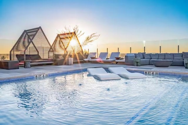 48 E Ave Unit 2707, Austin, TX 78701 - pool at dusk with an outdoor living space with a fireplace, a community pool, and a patio area