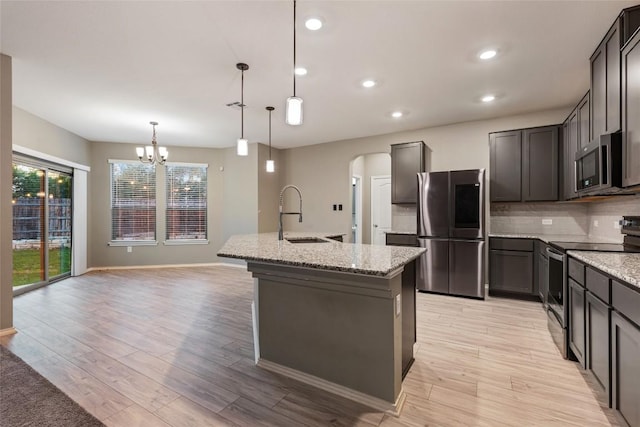 101 Crimson Ln, Kyle, TX 78640 - kitchen featuring stainless steel appliances, a chandelier, light stone countertops, arched walkways, and recessed lighting