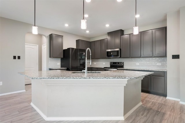 101 Crimson Ln, Kyle, TX 78640 - kitchen featuring appliances with stainless steel finishes, light stone counters, decorative backsplash, a center island with sink, and recessed lighting