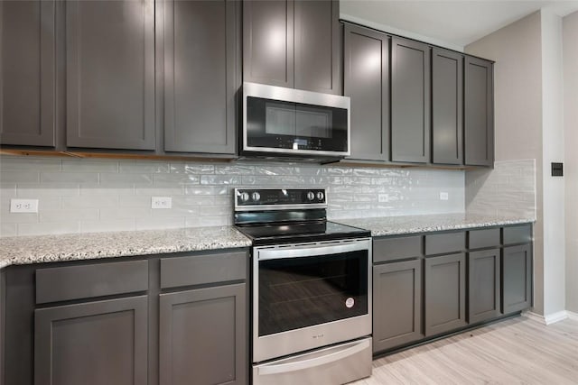 101 Crimson Ln, Kyle, TX 78640 - kitchen featuring appliances with stainless steel finishes, light wood-style flooring, gray cabinets, and light stone countertops