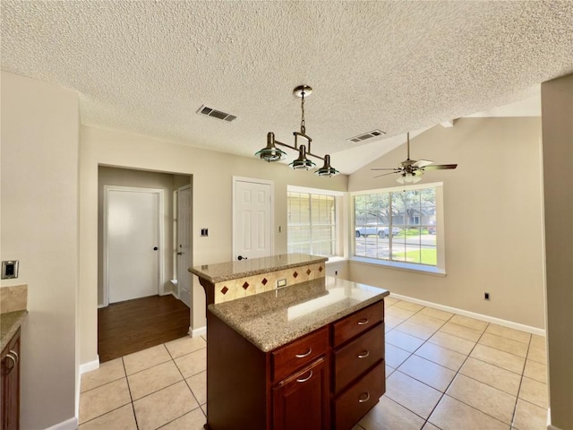 6400 Jennings Dr, Austin, TX 78727 - kitchen featuring light tile patterned floors, a kitchen island, a textured ceiling, ceiling fan, and light stone countertops