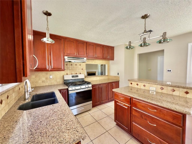 6400 Jennings Dr, Austin, TX 78727 - kitchen with stainless steel gas range, under cabinet range hood, backsplash, decorative light fixtures, and a textured ceiling