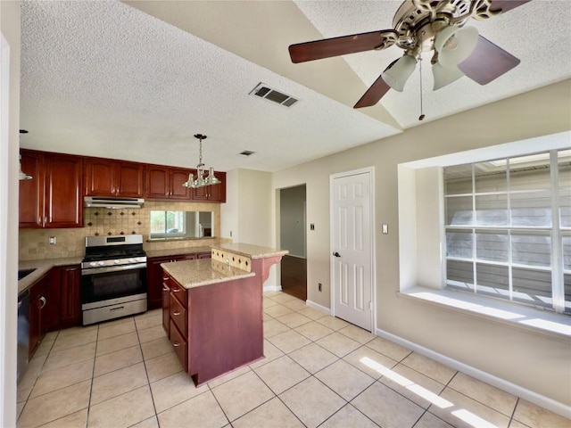6400 Jennings Dr, Austin, TX 78727 - kitchen featuring stainless steel range with gas cooktop, under cabinet range hood, a textured ceiling, backsplash, and light tile patterned floors