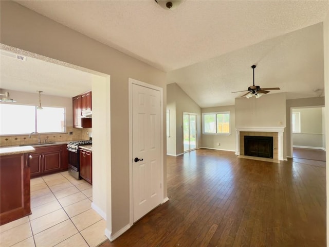 6400 Jennings Dr, Austin, TX 78727 - kitchen featuring gas stove, a ceiling fan, light countertops, light wood finished floors, and a tiled fireplace