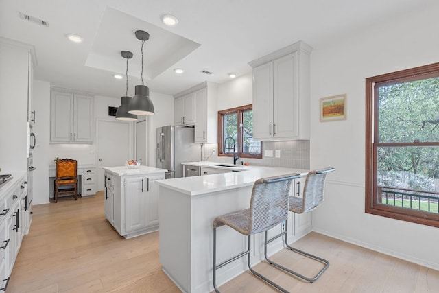 6302 Gato Path, Austin, TX 78731 - kitchen featuring freestanding refrigerator, light countertops, light wood-style floors, a center island, and a peninsula