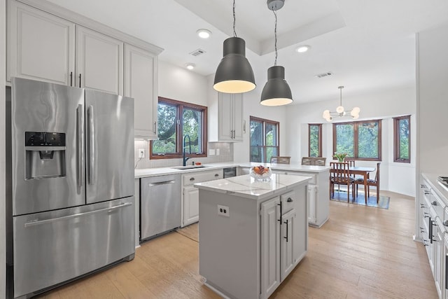 6302 Gato Path, Austin, TX 78731 - kitchen with stainless steel appliances, a peninsula, a kitchen island, light wood-style flooring, and tasteful backsplash