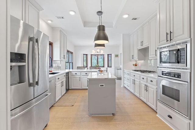 6302 Gato Path, Austin, TX 78731 - kitchen with appliances with stainless steel finishes, backsplash, a peninsula, a raised ceiling, and light wood-type flooring