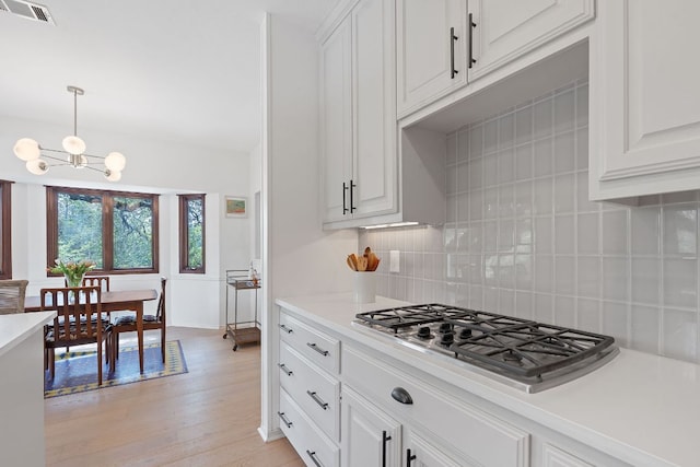 6302 Gato Path, Austin, TX 78731 - kitchen with tasteful backsplash, stainless steel gas cooktop, light wood finished floors, light countertops, and a chandelier