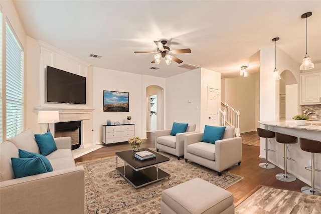 65 White Magnolia Cir, Lakeway, TX 78734 - living room with arched walkways, wood finished floors, ceiling fan, and stairway