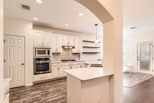 65 White Magnolia Cir, Lakeway, TX 78734 - kitchen featuring stainless steel appliances, arched walkways, dark wood-style floors, backsplash, and light countertops