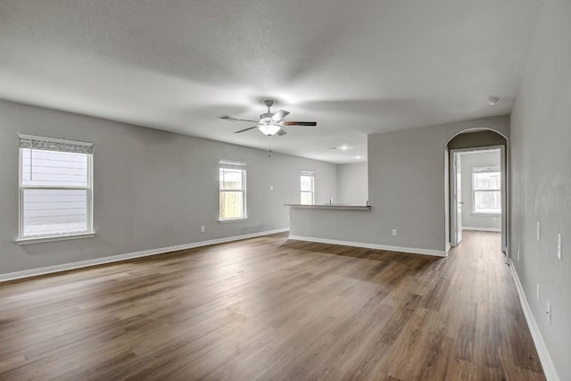1326 Amy Dr, Kyle, TX 78640 - unfurnished living room featuring arched walkways, ceiling fan, and wood finished floors