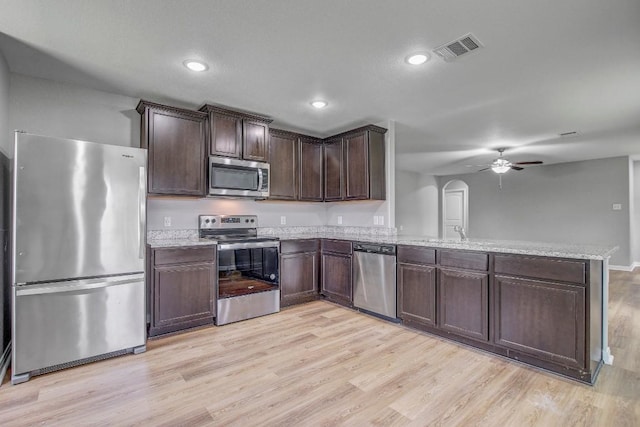 1326 Amy Dr, Kyle, TX 78640 - kitchen featuring appliances with stainless steel finishes, a peninsula, ceiling fan, light wood-style flooring, and dark brown cabinets