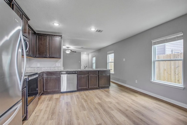 1326 Amy Dr, Kyle, TX 78640 - kitchen with appliances with stainless steel finishes, light wood-type flooring, dark brown cabinets, a peninsula, and ceiling fan