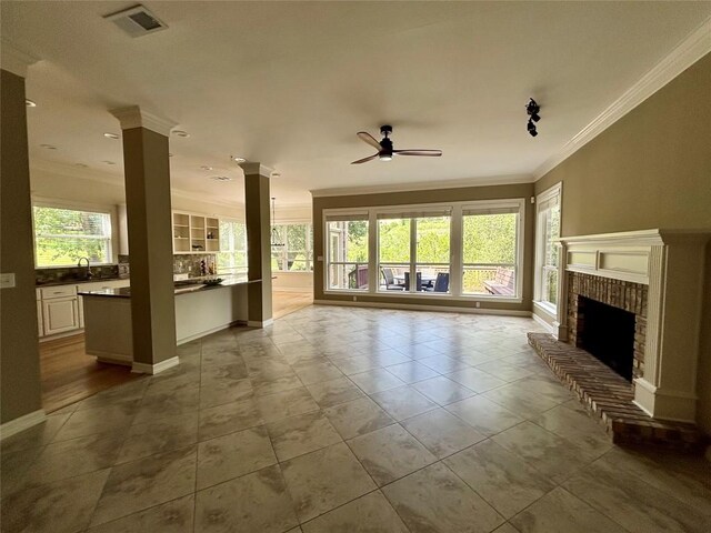 1733 Canonero Dr, Austin, TX 78746 - unfurnished living room with crown molding, a ceiling fan, ornate columns, a fireplace, and tile patterned floors