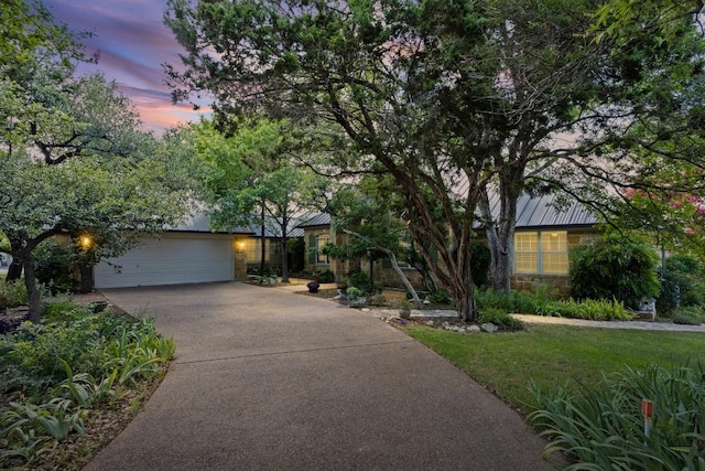 100 Broad Vista Ct, Georgetown, TX 78628 - view of property hidden behind natural elements with stone siding, driveway, a standing seam roof, a garage, and a metal roof
