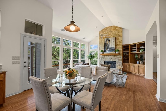 100 Broad Vista Ct, Georgetown, TX 78628 - dining room featuring a fireplace, wood finished floors, high vaulted ceiling, ceiling fan, and arched walkways