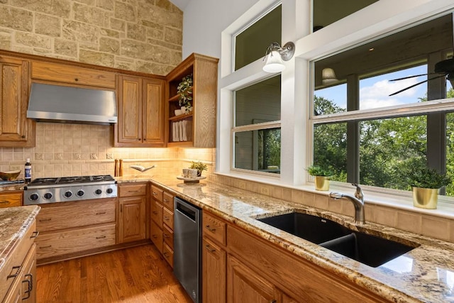 100 Broad Vista Ct, Georgetown, TX 78628 - kitchen with appliances with stainless steel finishes, under cabinet range hood, brown cabinets, tasteful backsplash, and light stone countertops