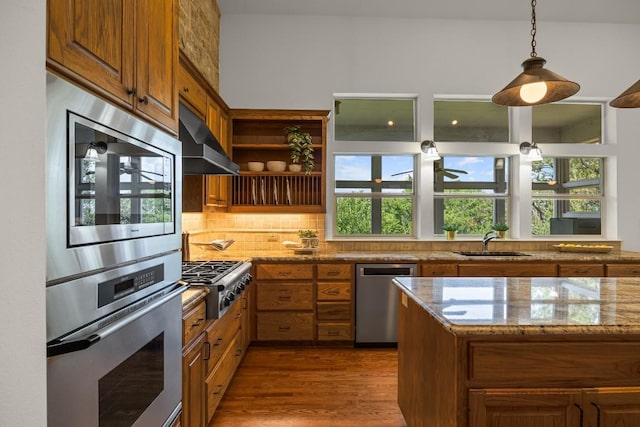 100 Broad Vista Ct, Georgetown, TX 78628 - kitchen with stainless steel appliances, extractor fan, brown cabinets, and light stone counters