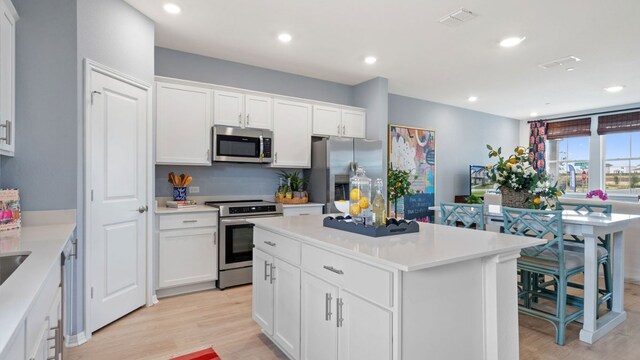 2528 Ophelia Levi Ln, Round Rock, TX 78665 - kitchen featuring stainless steel appliances, light wood-type flooring, white cabinetry, a kitchen island, and recessed lighting