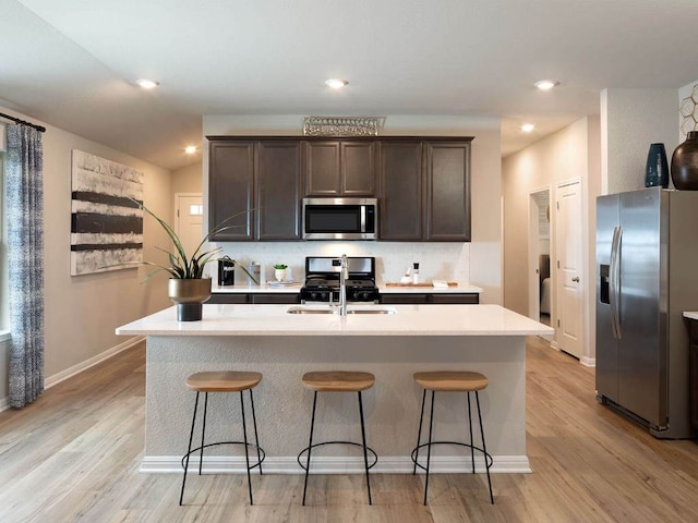 720 Sun Grove Trl, Georgetown, TX 78628 - kitchen featuring stainless steel appliances, dark brown cabinetry, tasteful backsplash, light countertops, and light wood-style flooring