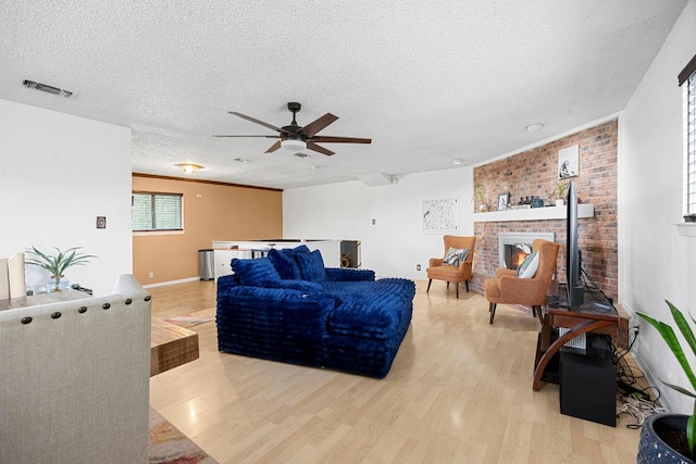 706 Cambridge Dr, Round Rock, TX 78664 - living room with light wood-style flooring, ceiling fan, a textured ceiling, and a brick fireplace