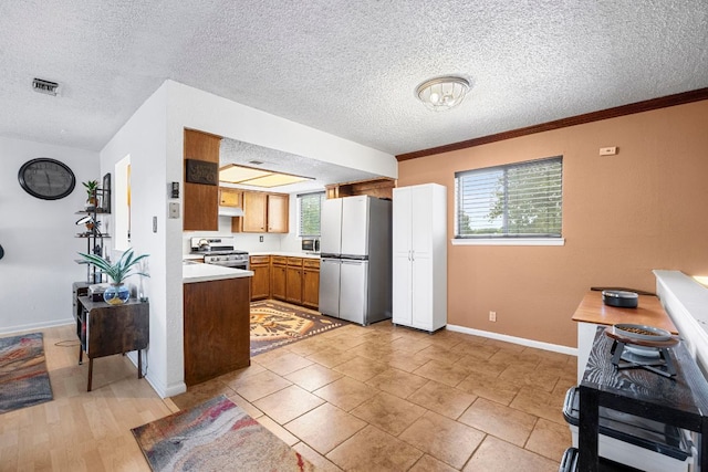 706 Cambridge Dr, Round Rock, TX 78664 - kitchen featuring freestanding refrigerator, stainless steel range with electric stovetop, light countertops, brown cabinets, and a textured ceiling